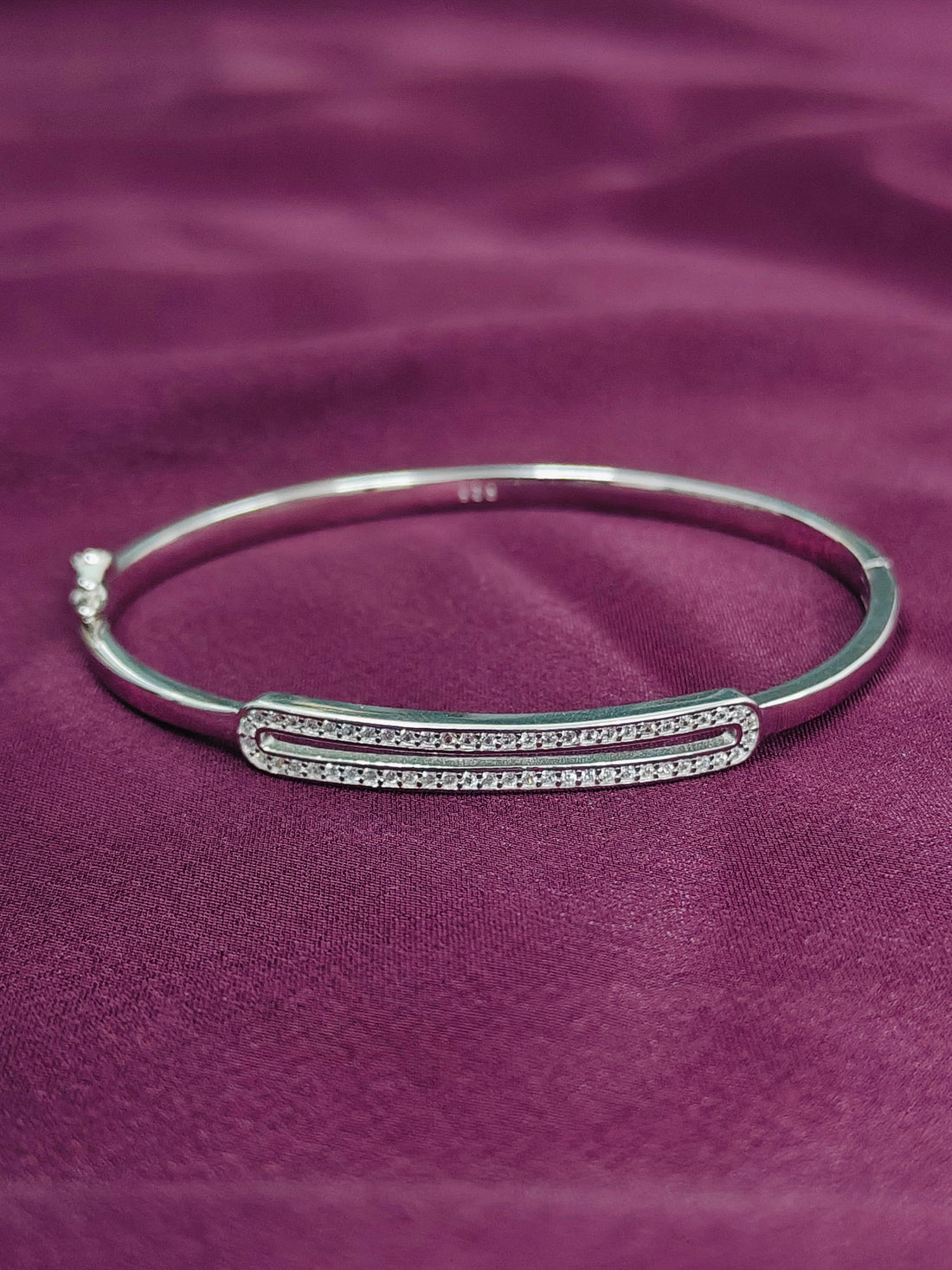 Silver bracelet with a bar design on a purple fabric background