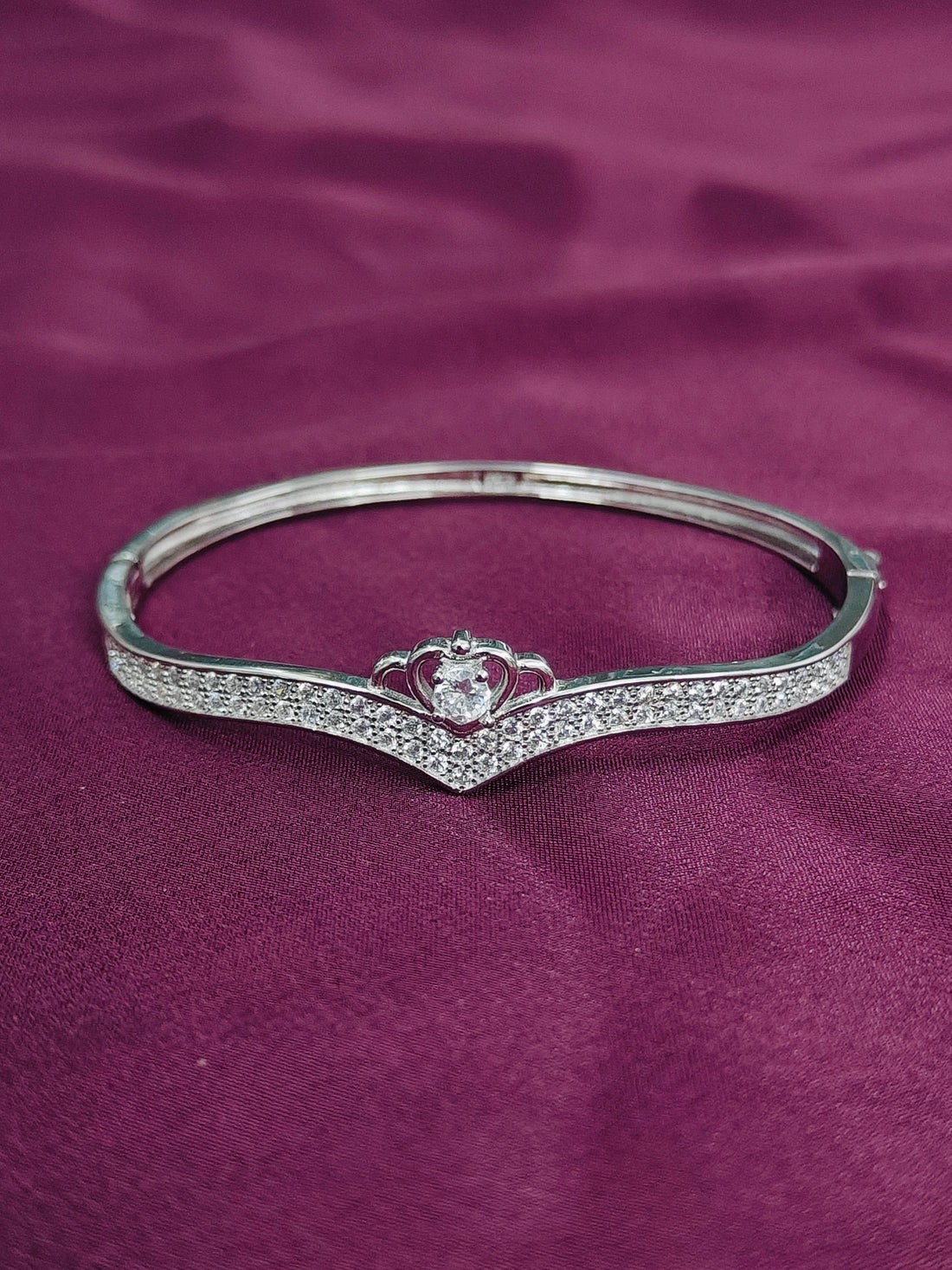 Silver bracelet with a heart design on a purple fabric background