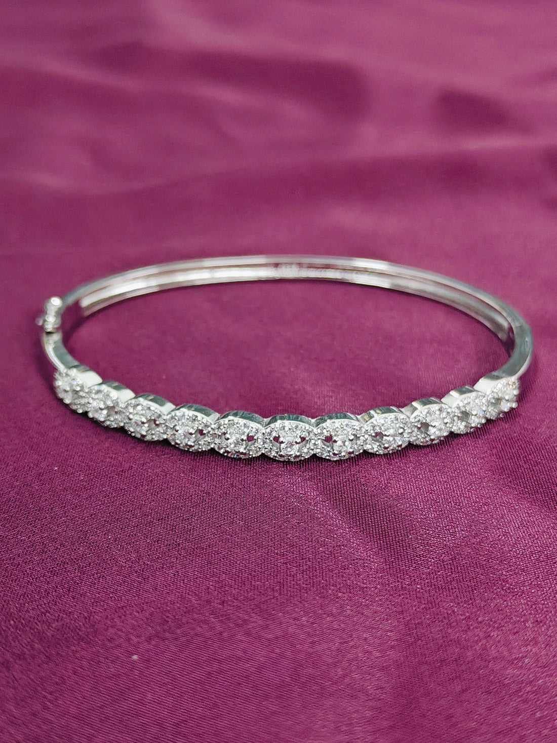 Silver bracelet with clear stones on a purple fabric background