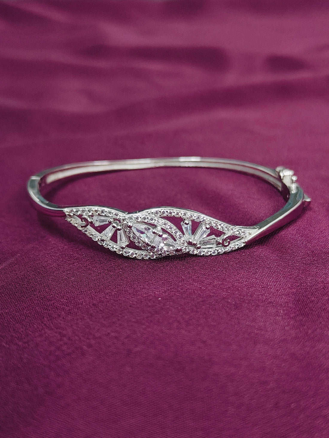 Silver bracelet with intricate design on a purple fabric background