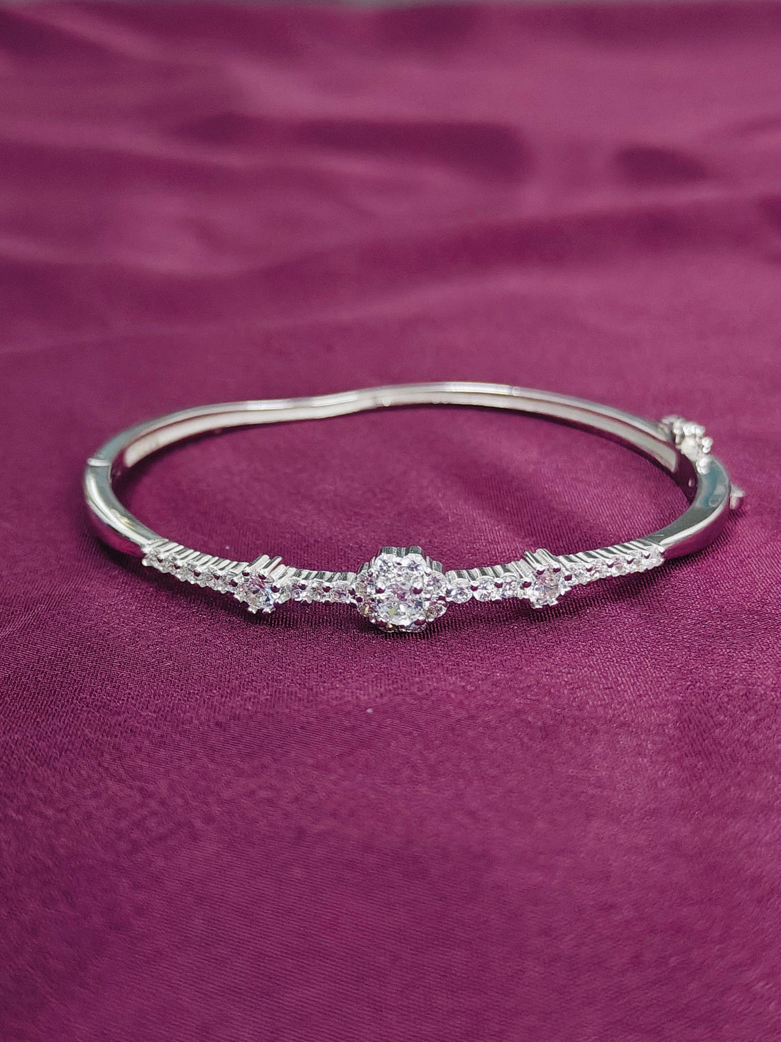 Silver bracelet with a central diamond on a purple fabric background