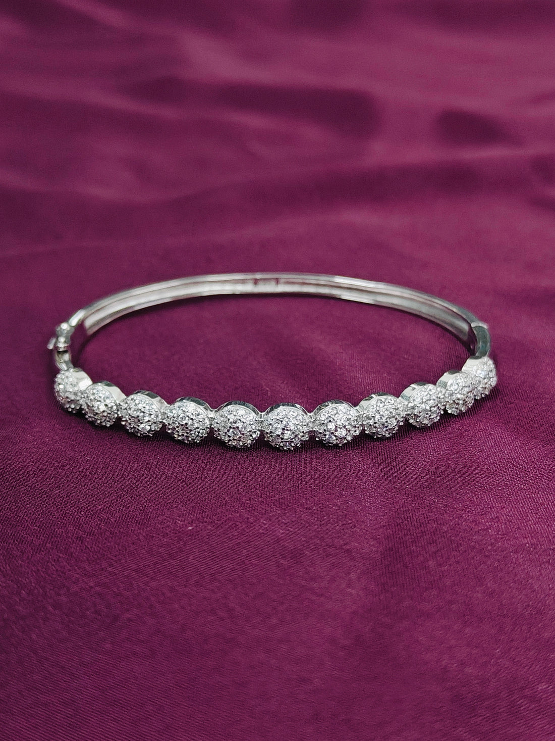 Silver bracelet with beaded design on a purple fabric background