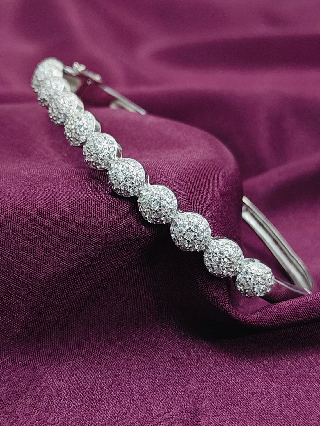 Silver bracelet with clear stones on a purple fabric background