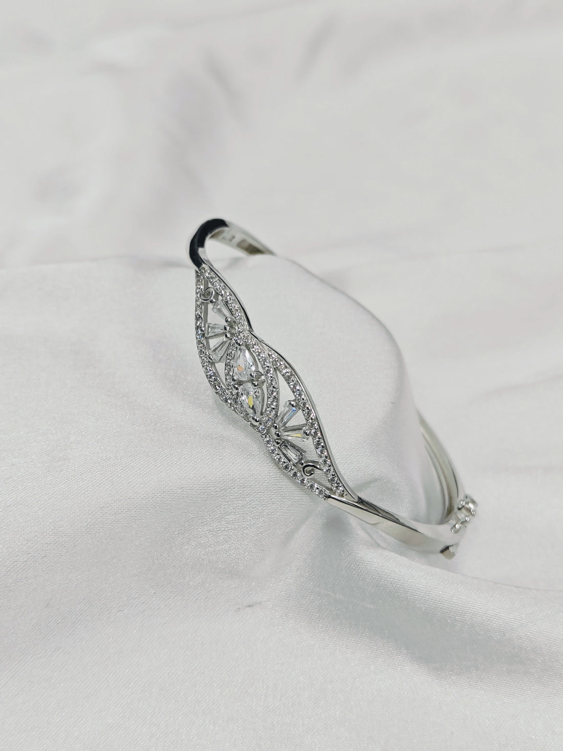 Silver bracelet with intricate design on a white fabric background