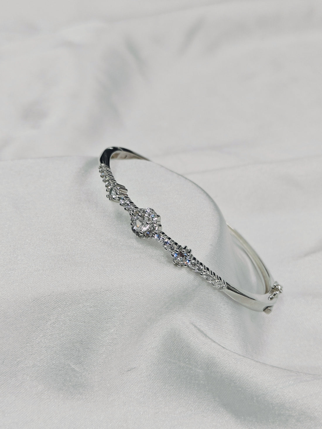 Silver bracelet with clear stones on a light gray background