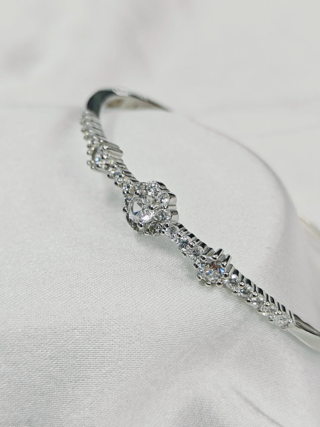 Silver bracelet with clear gemstones on a light gray background
