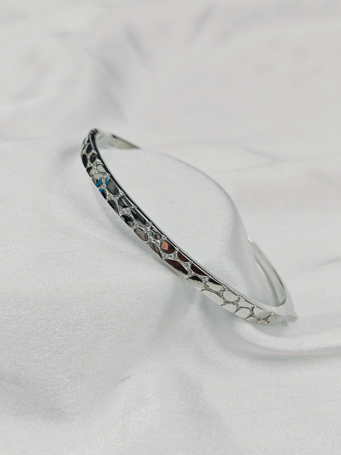 Silver bracelet with marbled design on a white background