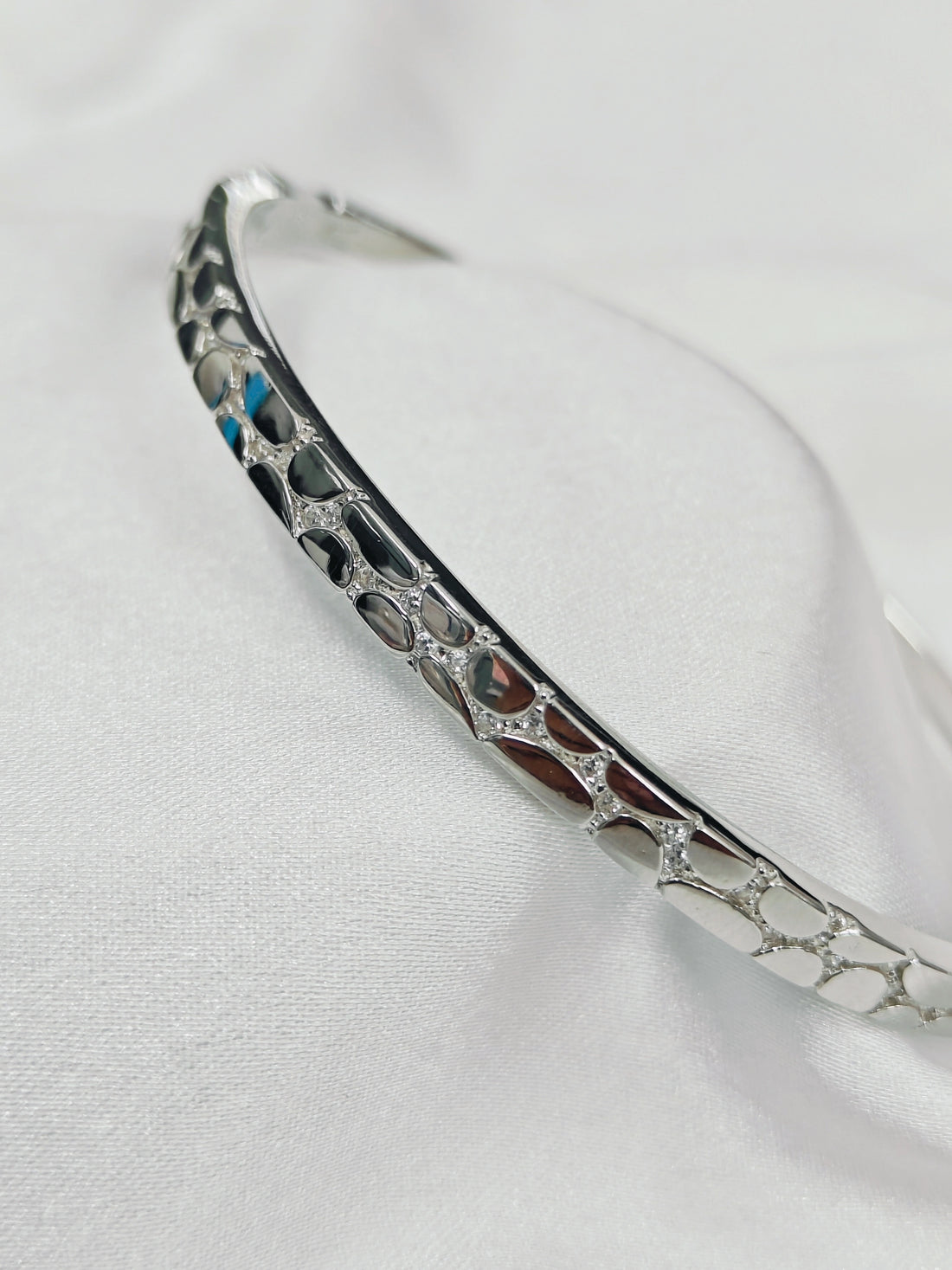 Silver bracelet with intricate design on a white background