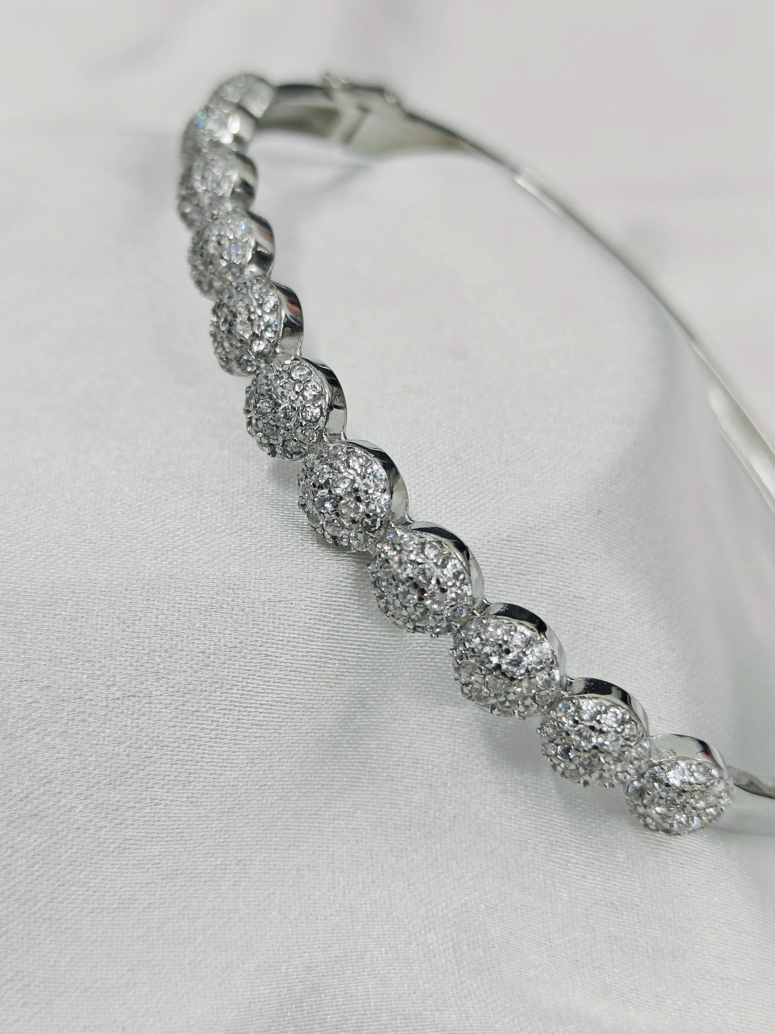 Silver bracelet with clear stones on a light gray background