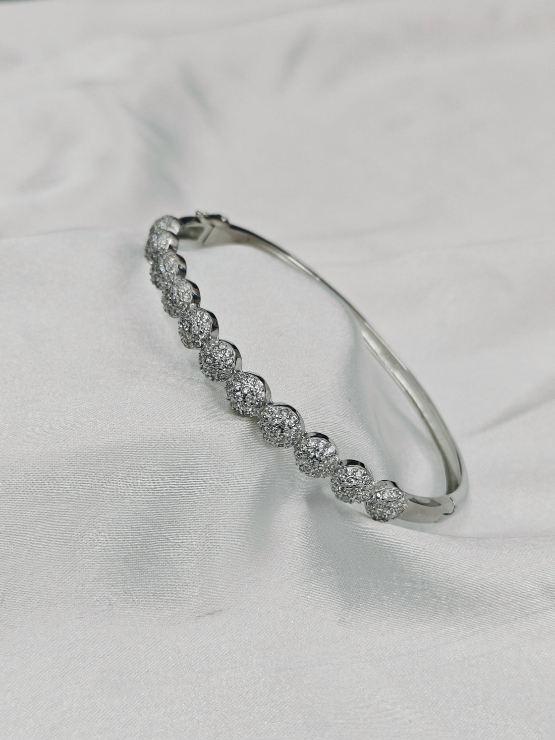 Silver bracelet with clear stones on a white fabric background