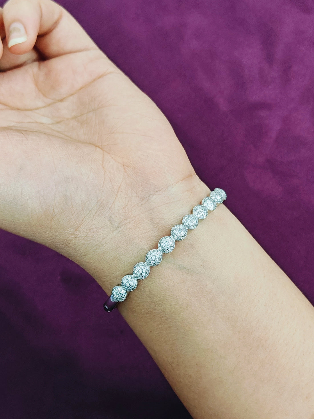 Silver bracelet on a wrist against a purple background