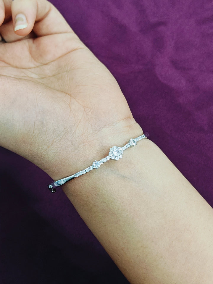 Silver bracelet on a wrist with a purple background