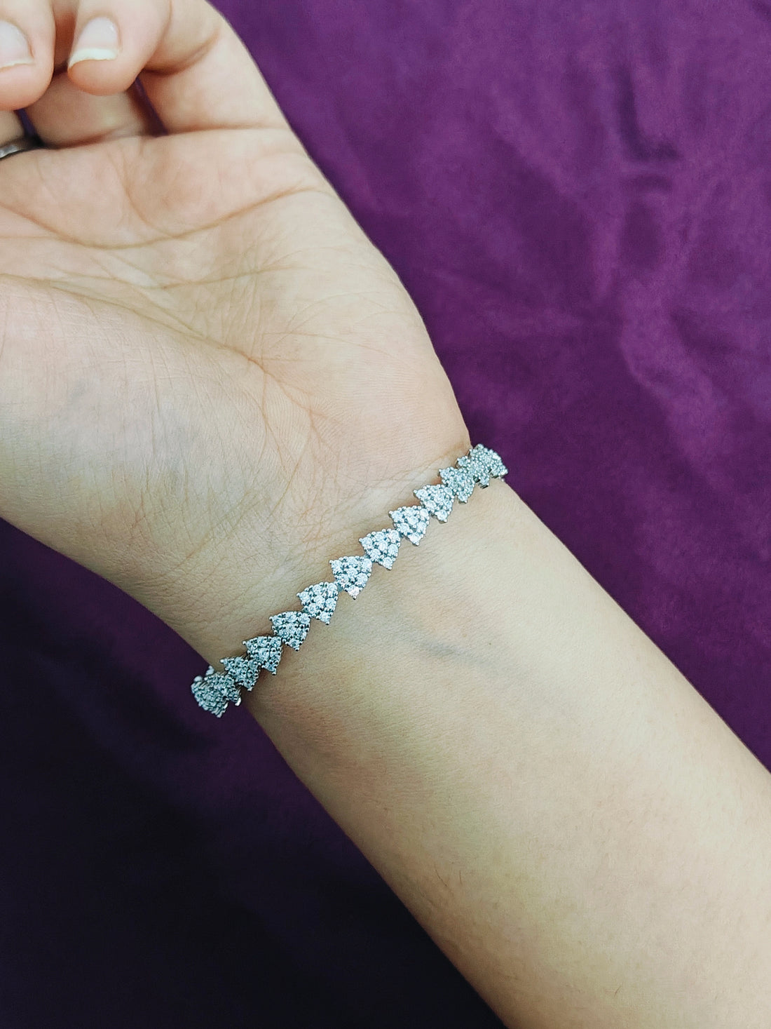 Silver bracelet on a person's wrist against a purple background