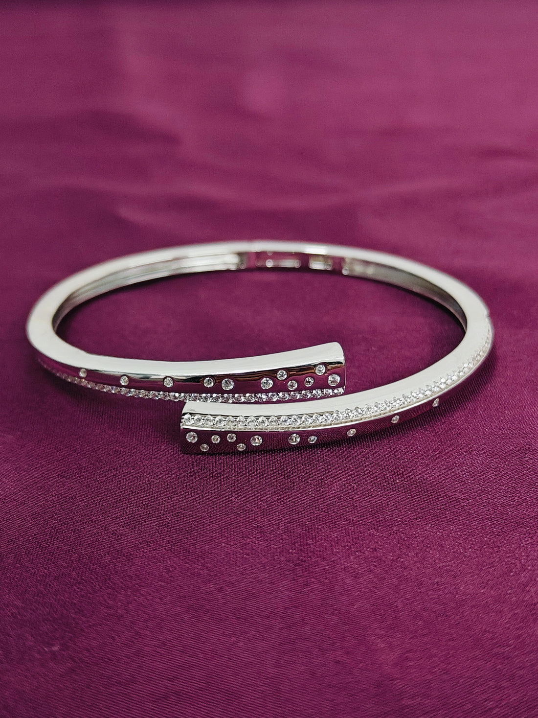 Silver bracelet with small stones on a purple fabric background