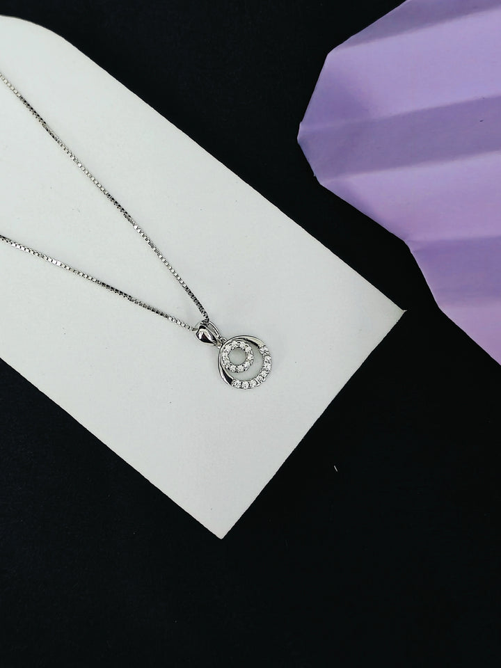 Silver necklace with a circular pendant on a white card against a black background