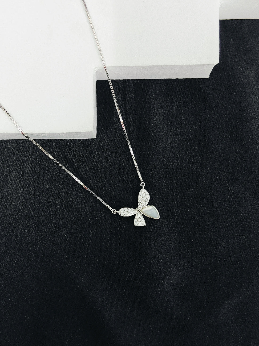 Silver butterfly necklace on a black background