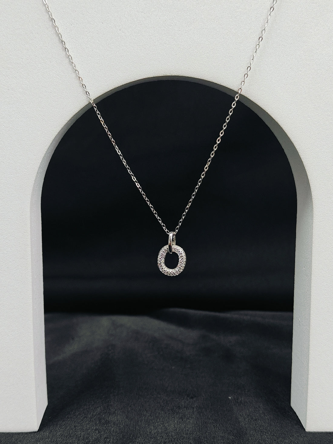 Silver necklace with a circular pendant on a dark background