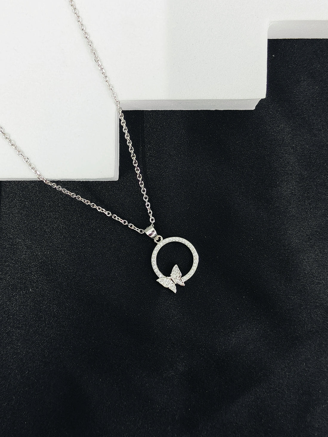 Silver necklace with a butterfly pendant on a black stand