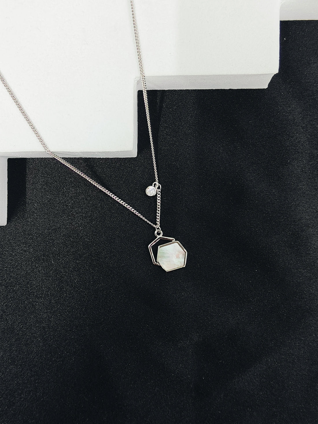 Necklace with a geometric pendant on a black surface