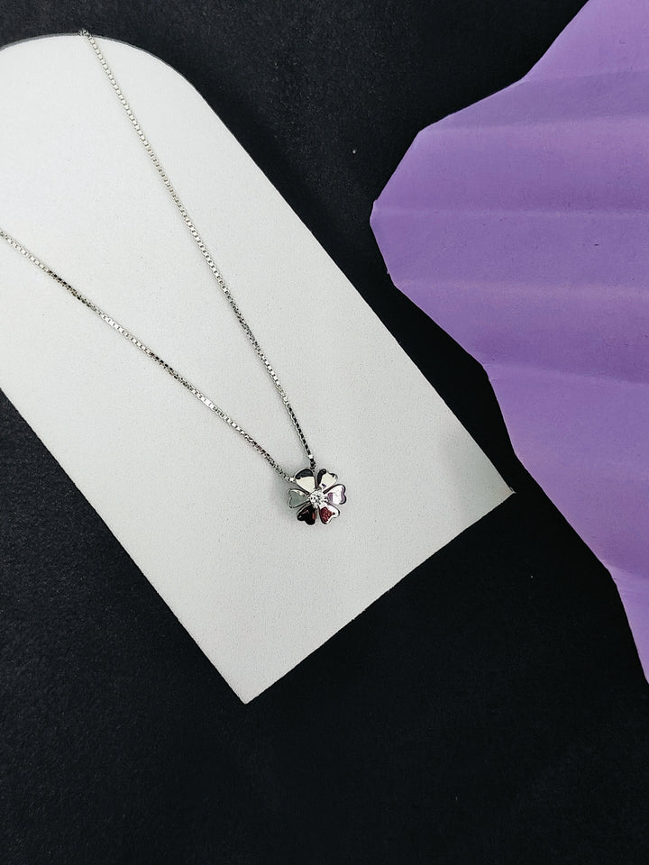 Silver necklace with a heart pendant on a white card against a black and purple background