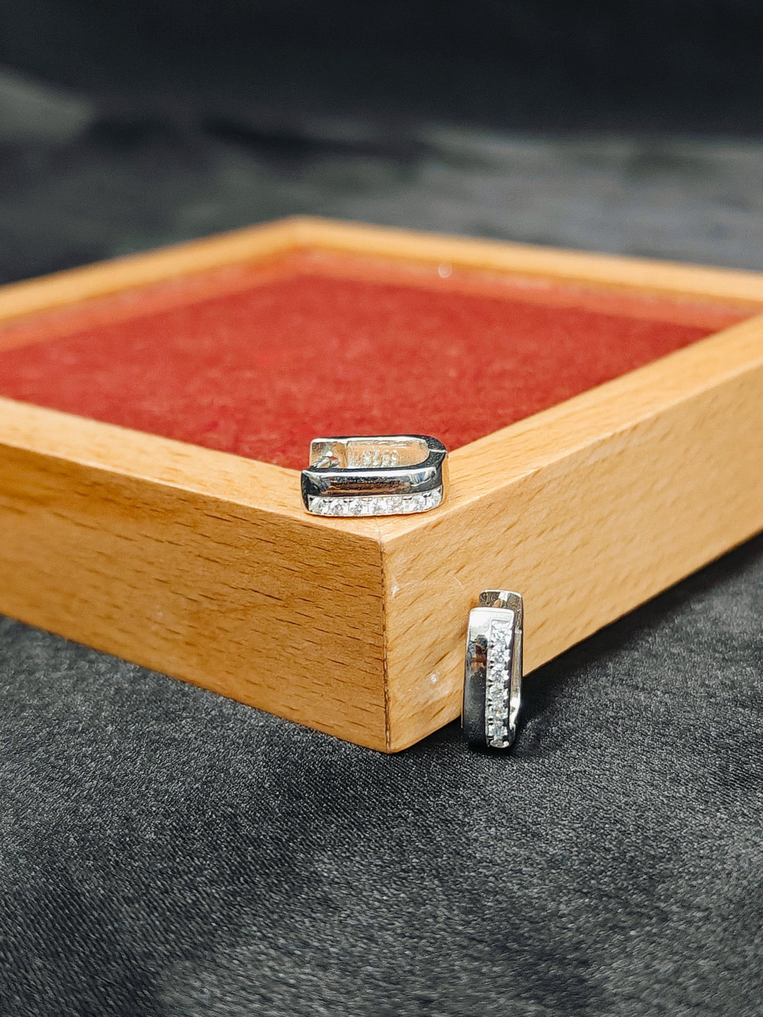 Silver rings on a wooden box with a red interior