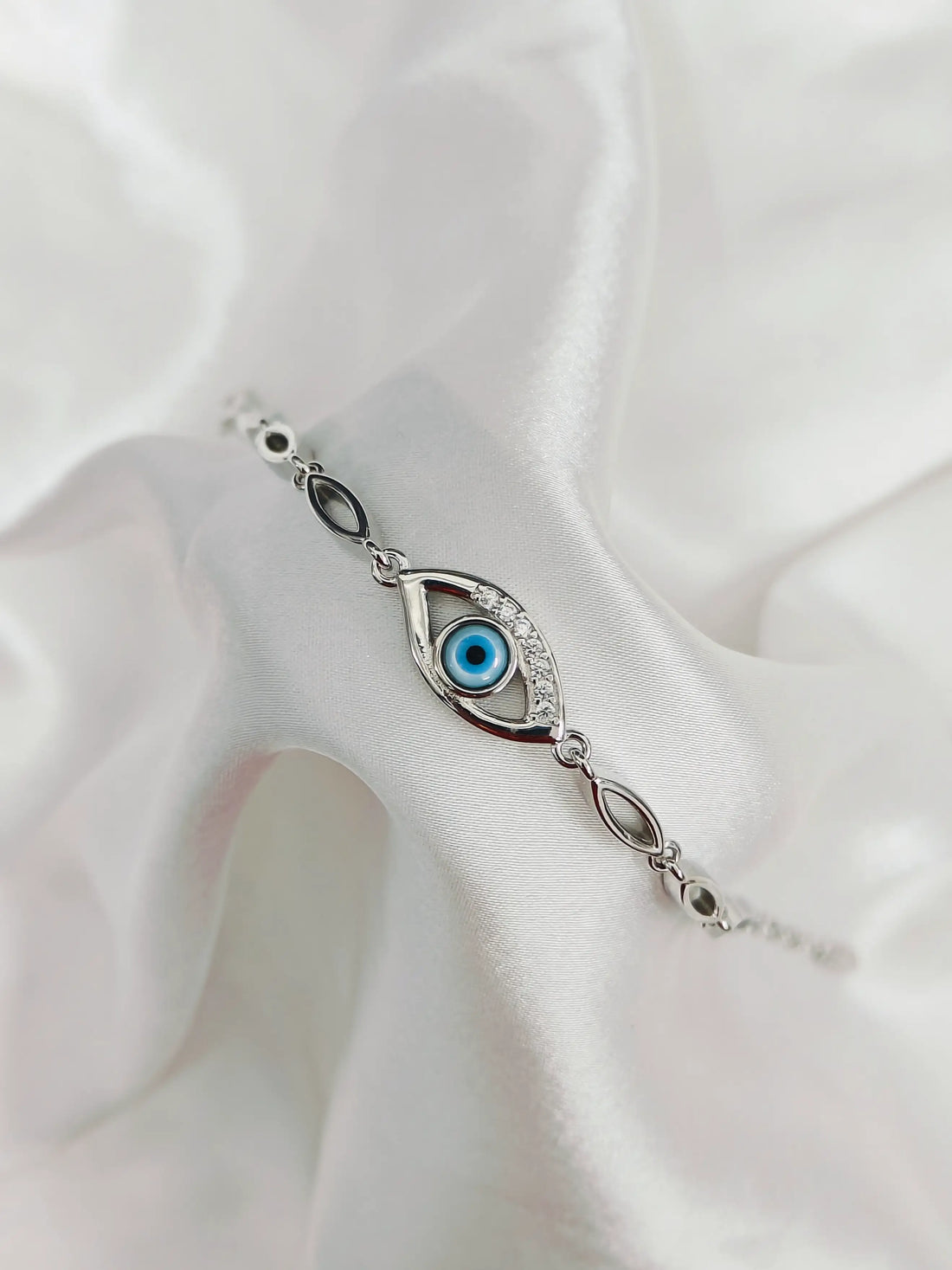 Silver bracelet with eye design on a white fabric background