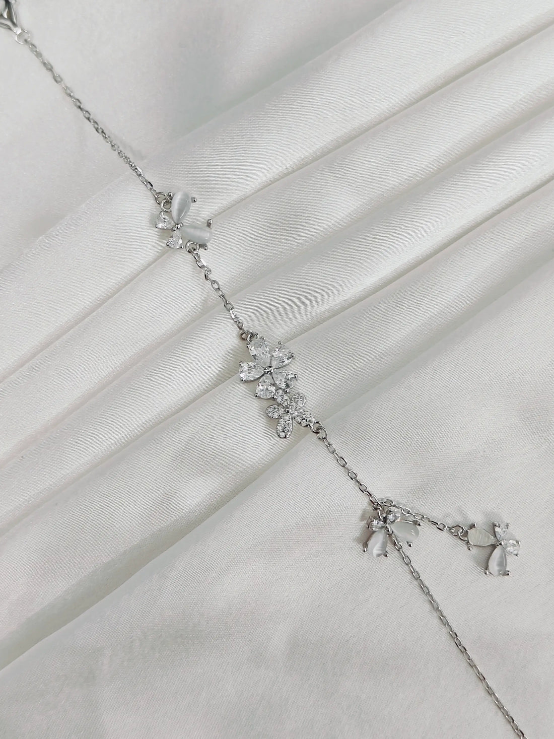 Silver necklace with floral design on a white fabric background