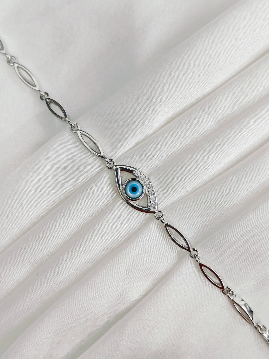 Silver bracelet with an eye design on a white fabric background