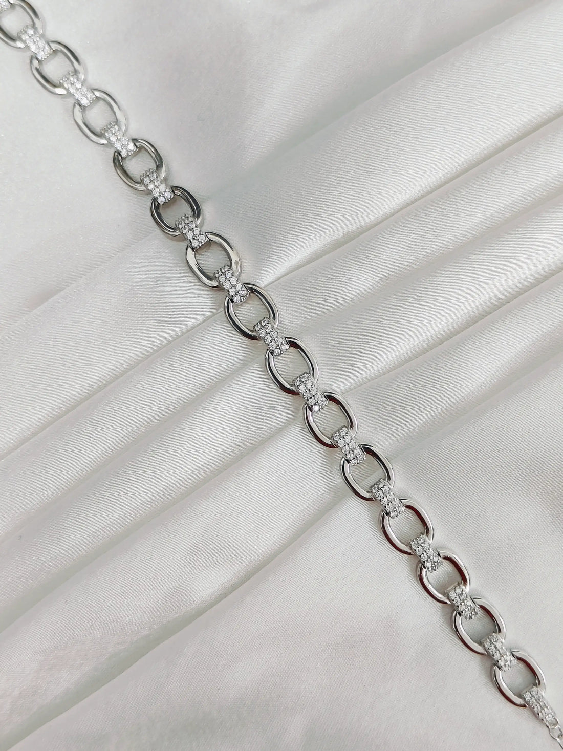 Silver chain necklace on a white fabric background