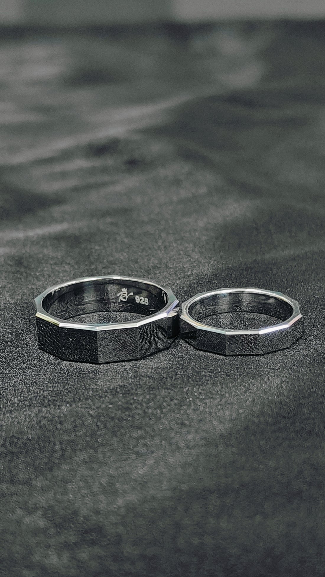 Two silver rings on a textured black surface