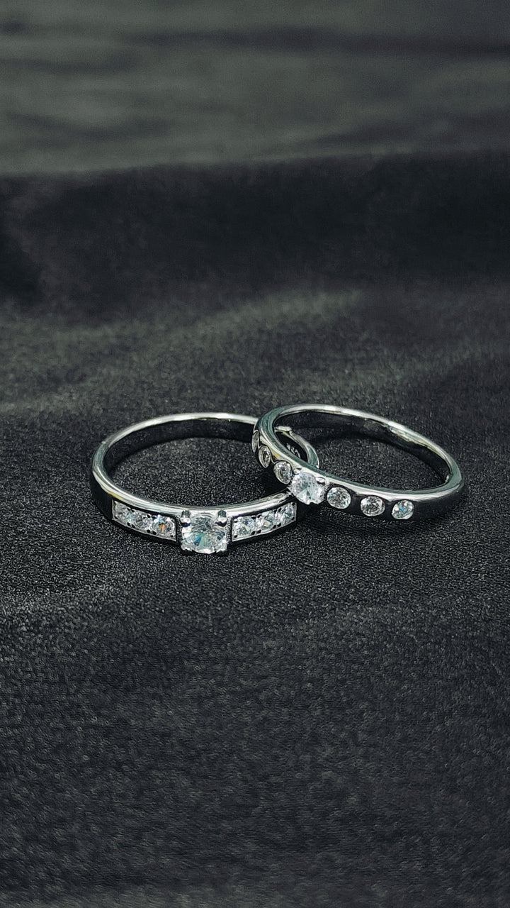 Two silver rings with gemstones on a black fabric background