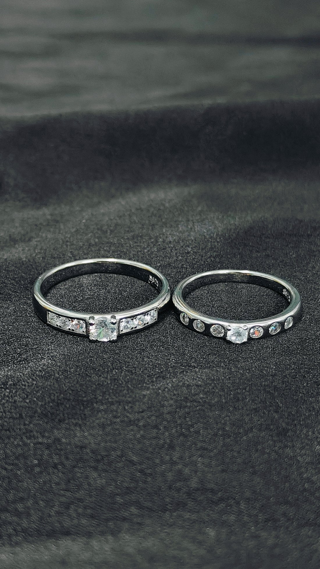 Two silver rings with gemstones on a dark fabric background