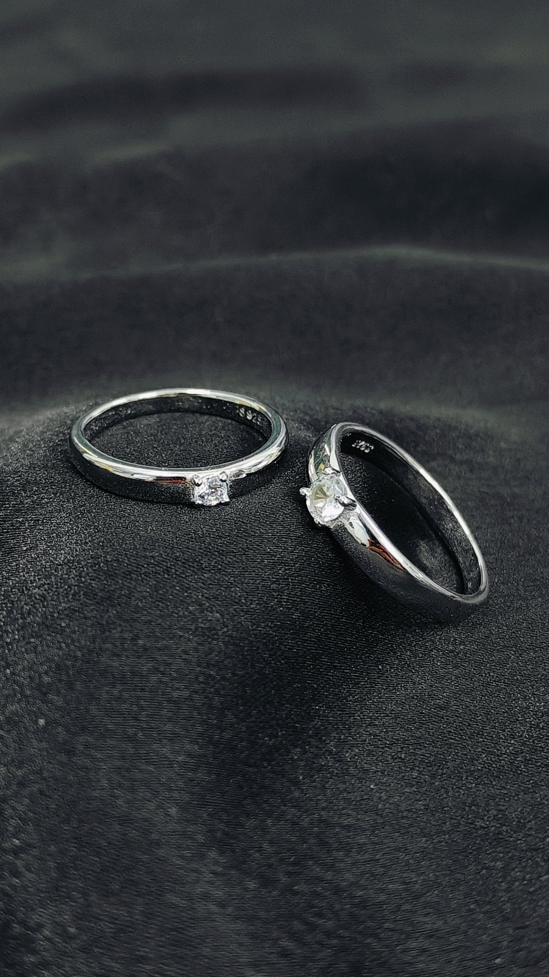 Two rings with gemstones on a dark fabric background