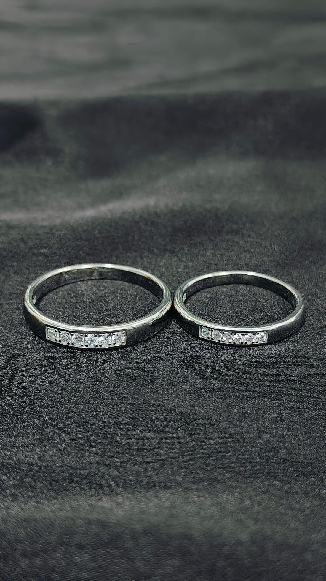 Two silver rings with gemstones on a textured black surface