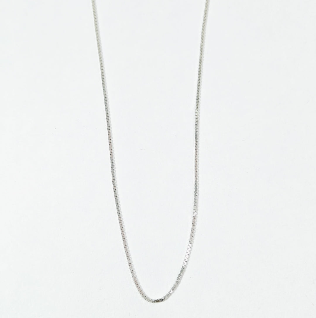 Silver chain necklace on a light gray background