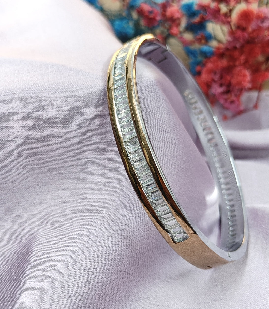 Gold and silver ring with diamond accents on a light pink fabric background