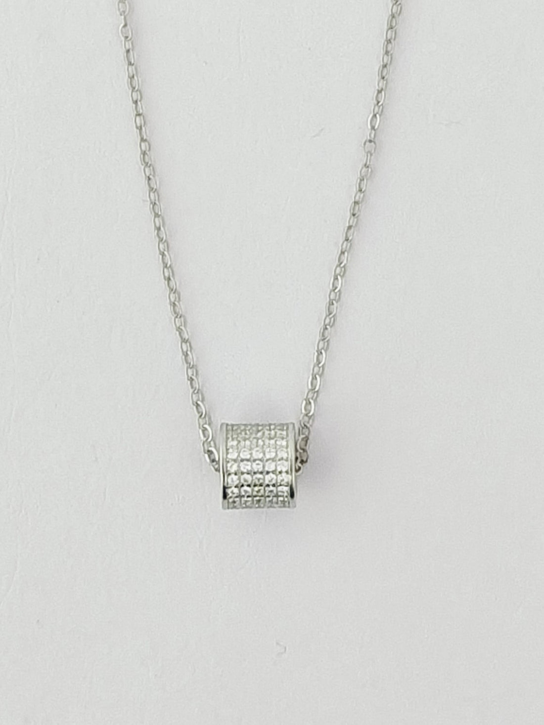 Silver necklace with a square pendant on a light gray background