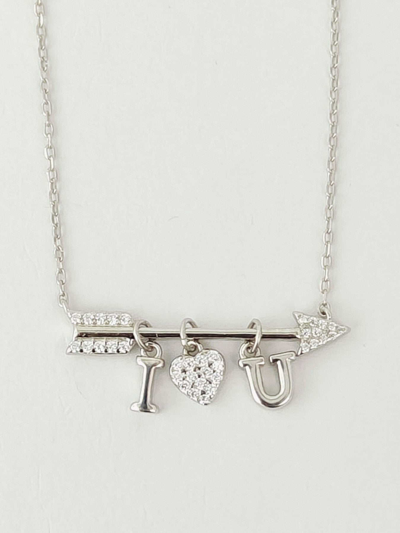 Silver necklace with 'I ❤️ U' charms on a light gray background