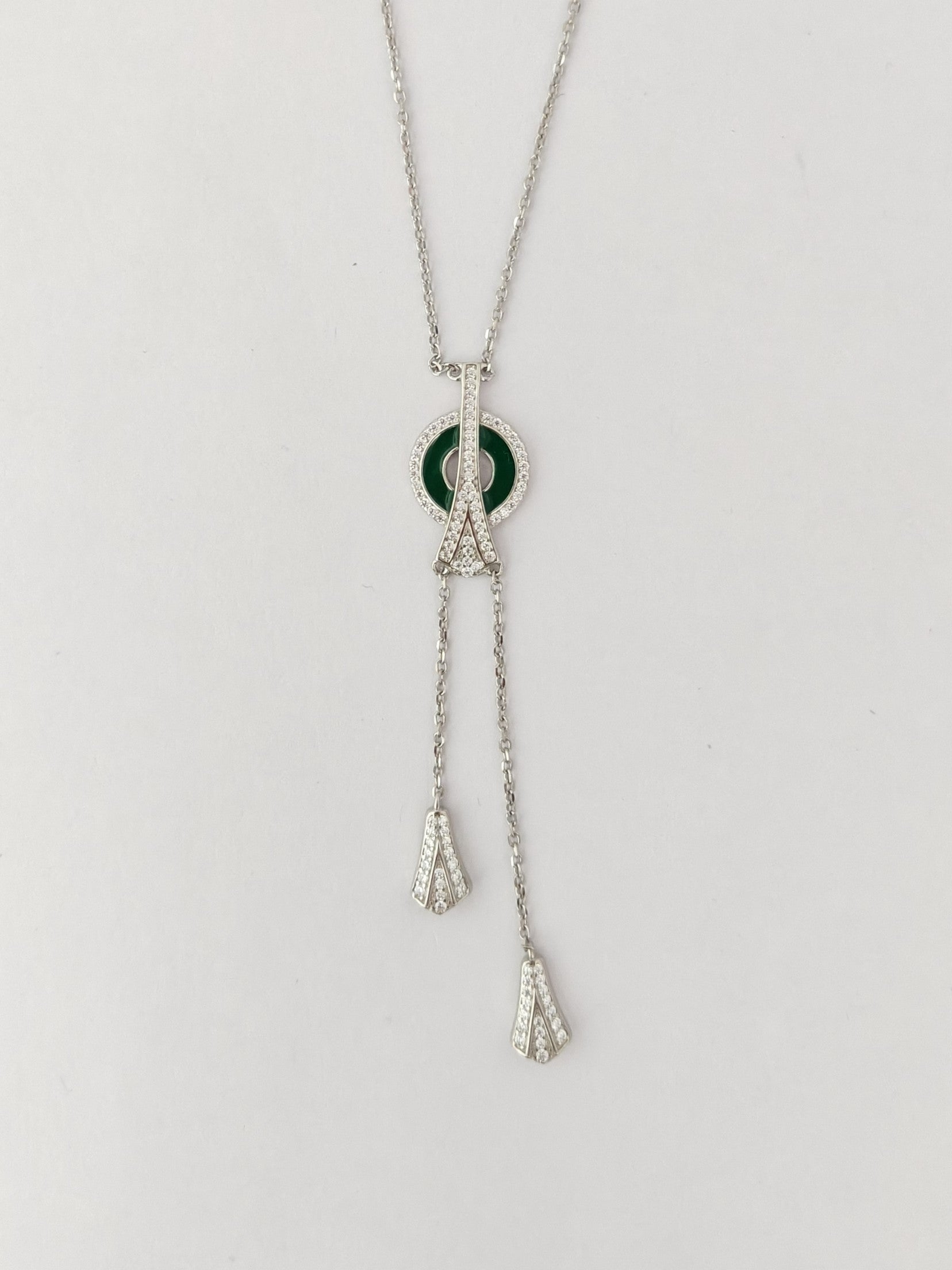 Necklace with a green pendant and silver chain on a light gray background