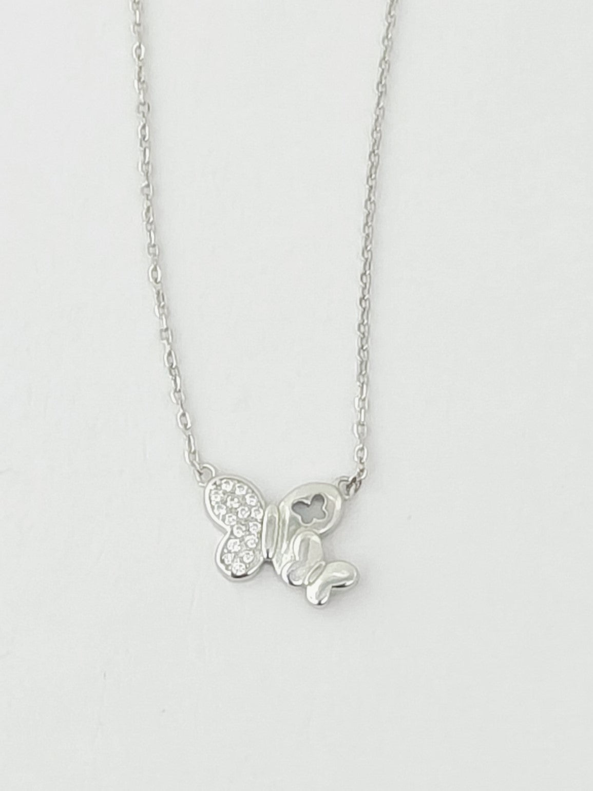 Silver butterfly necklace on a light gray background