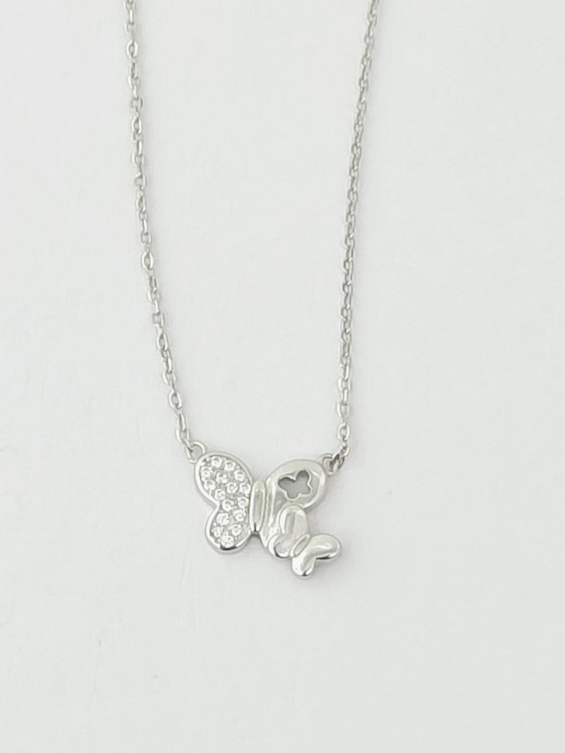 Silver butterfly necklace on a light gray background