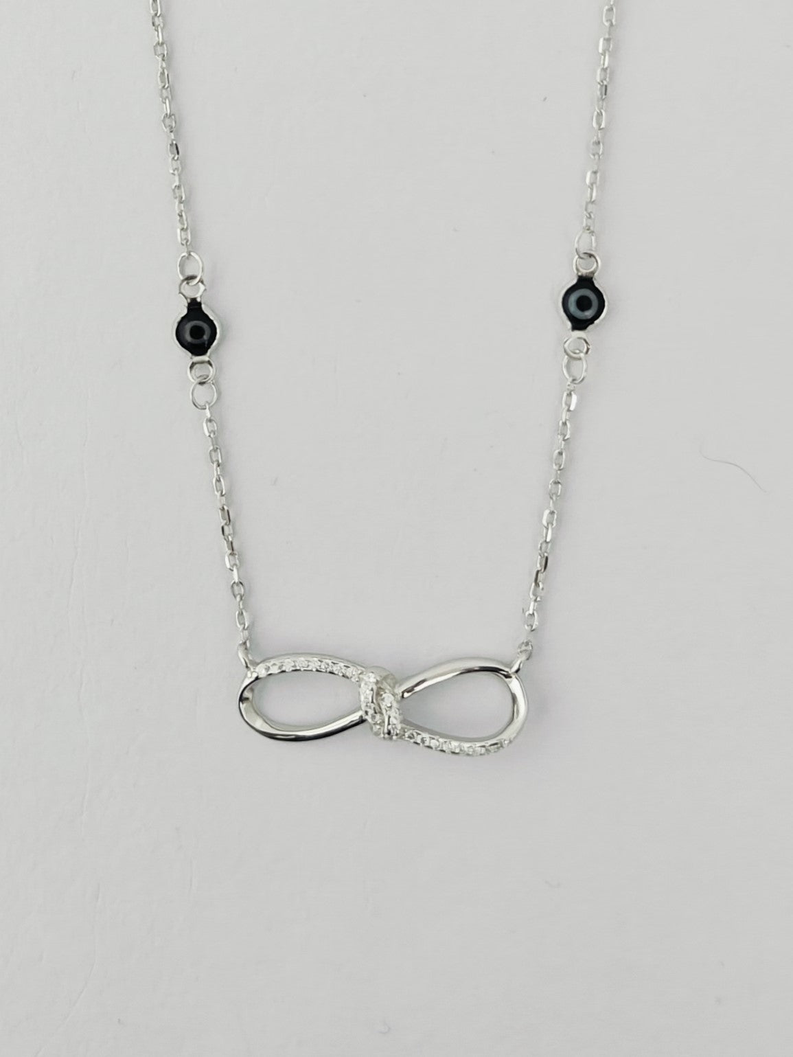 Silver infinity necklace with black beads on a light gray background
