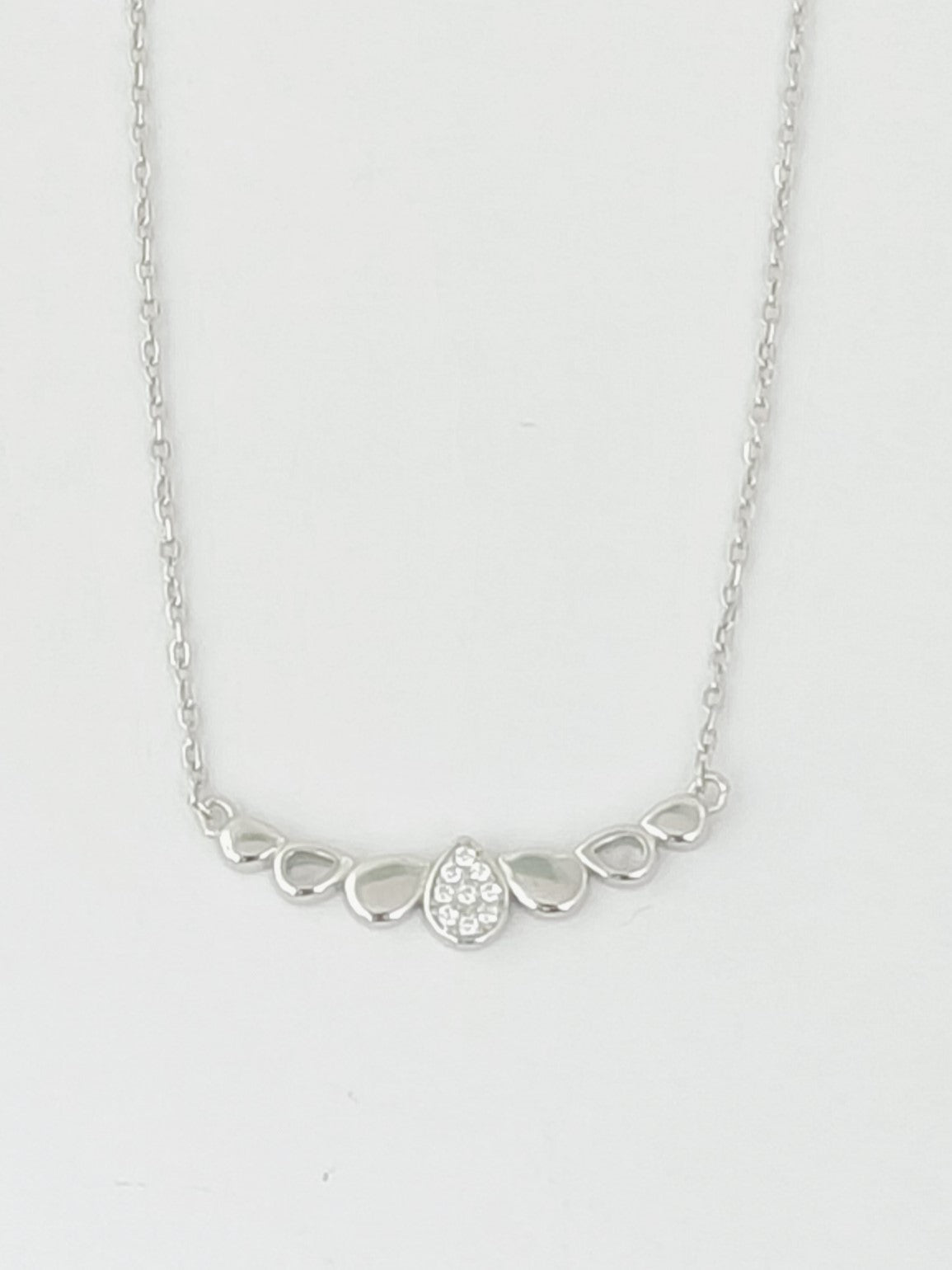 Silver necklace with a small round pendant on a light gray background