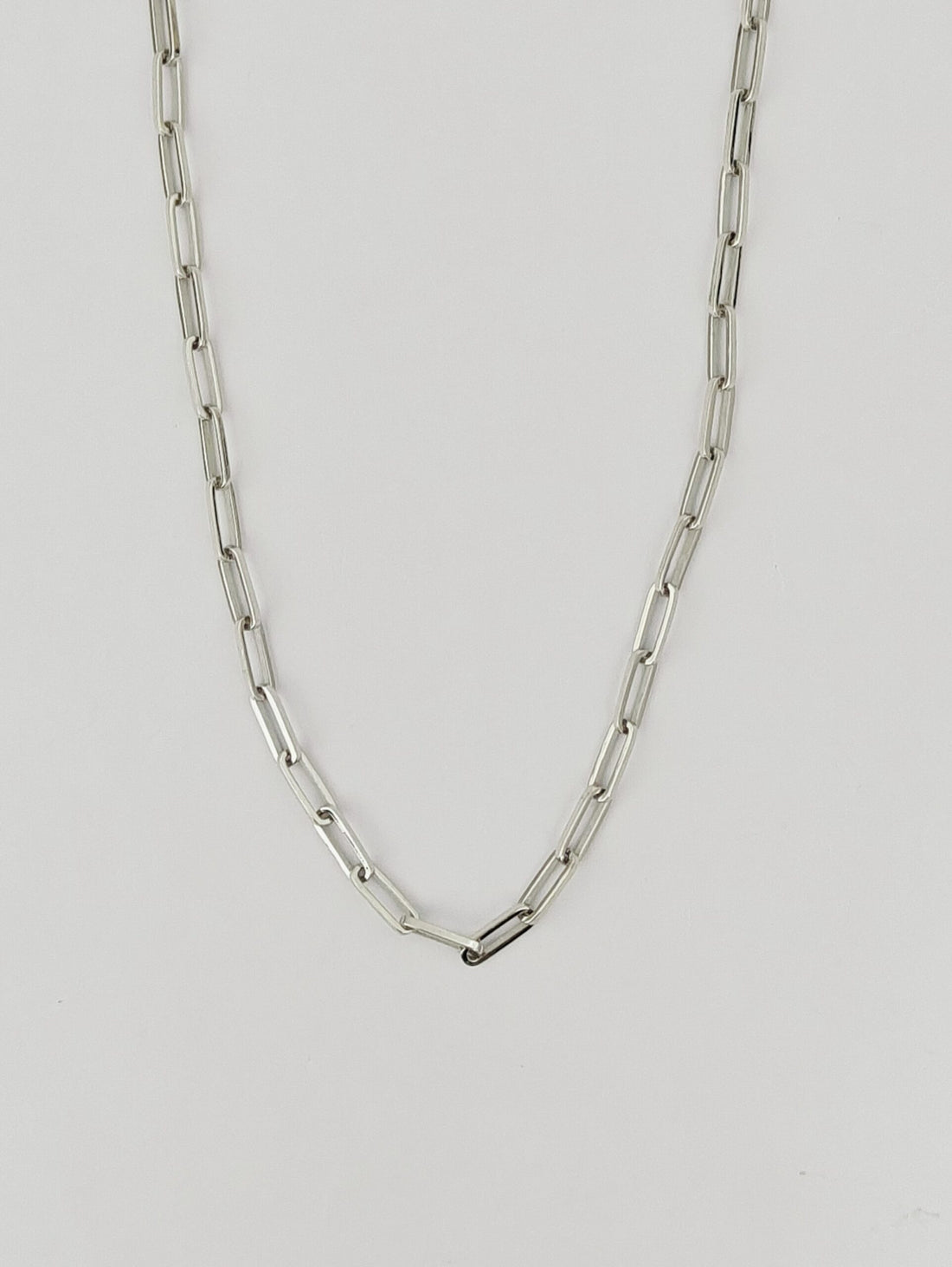 Silver chain necklace on a light gray background
