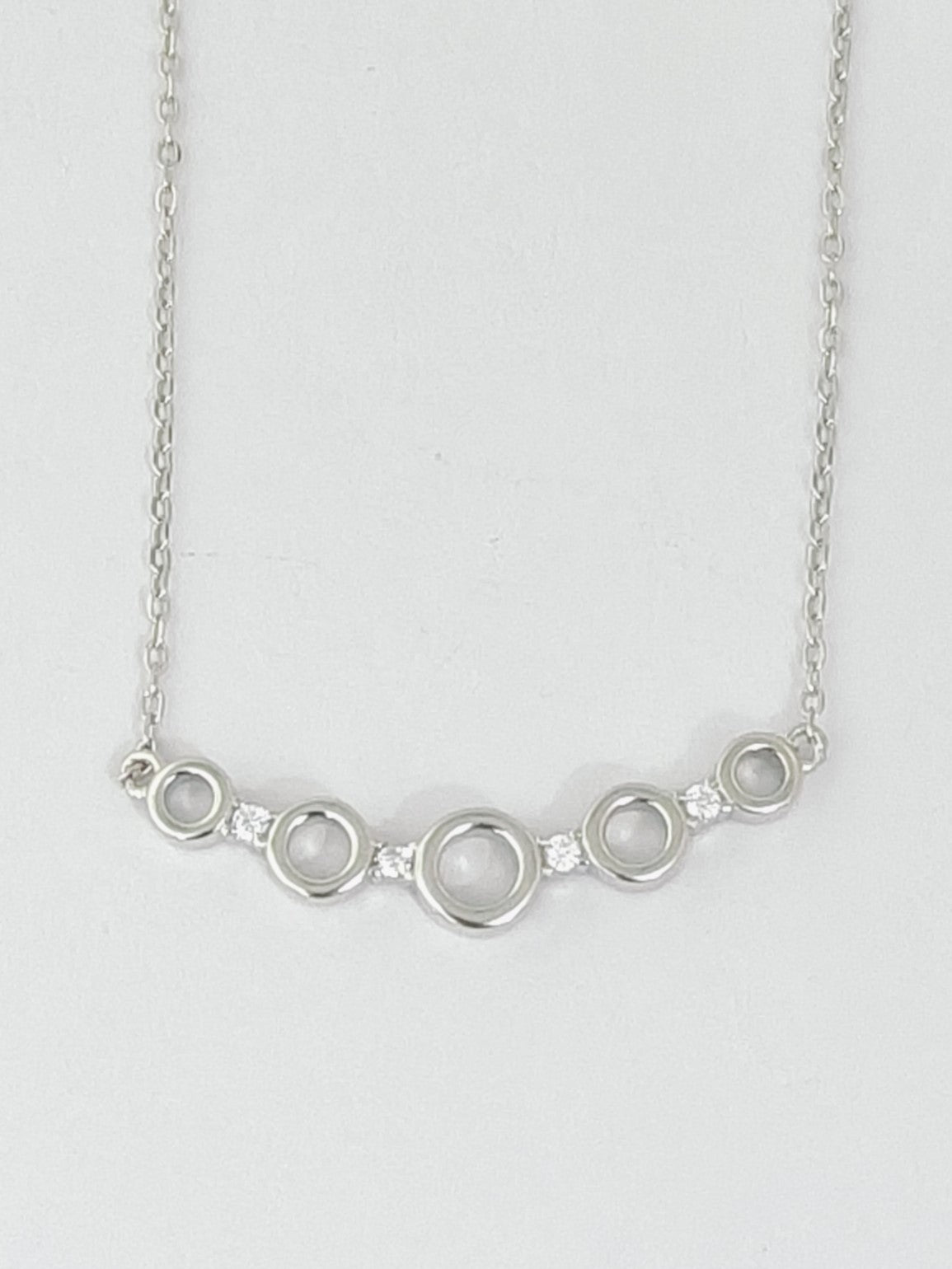 Silver necklace with circular design on a light gray background
