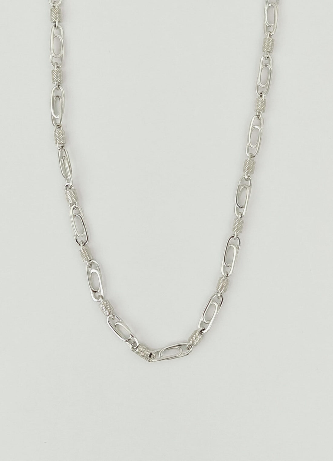 Silver chain necklace on a light gray background