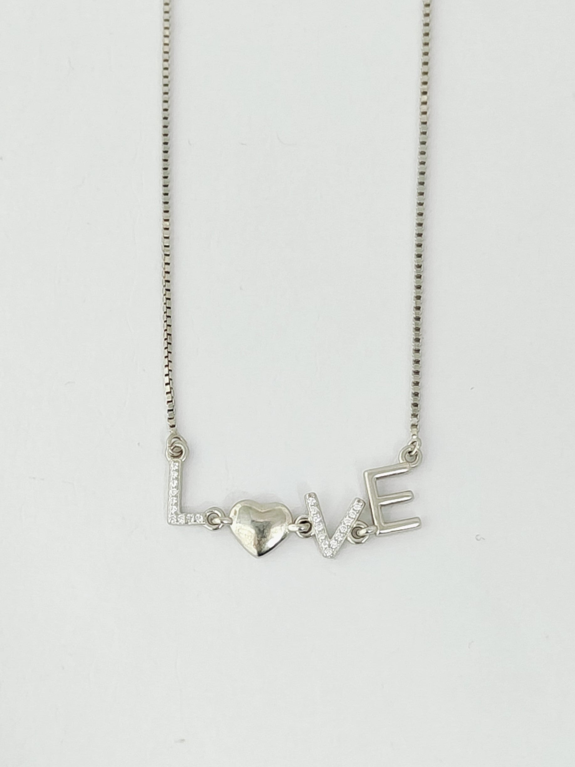 Silver necklace with 'LOVE' and heart pendant on a white background