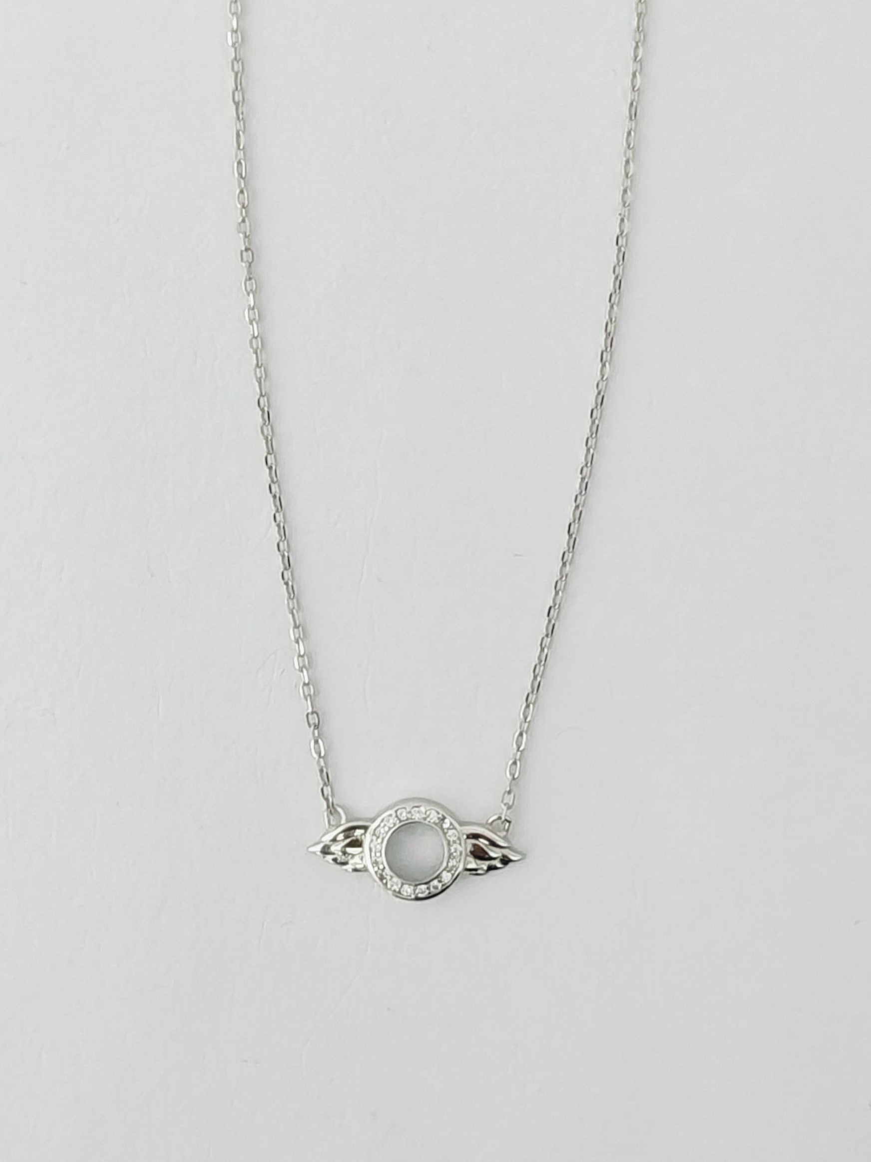 Silver necklace with a circular pendant on a light gray background