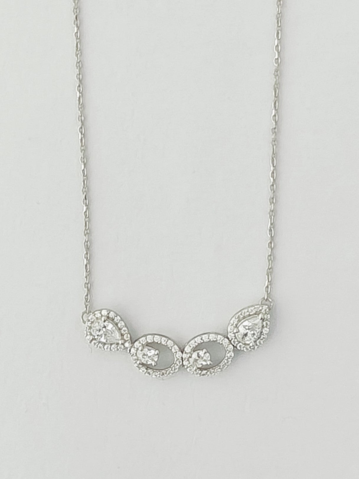 Silver necklace with three circular pendants on a light gray background