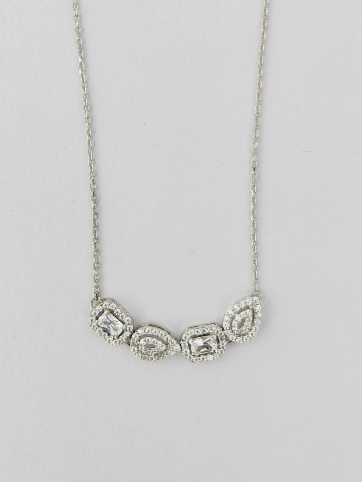 Silver necklace with three teardrop-shaped pendants on a light gray background